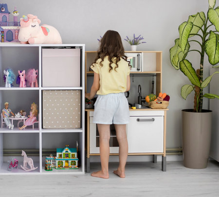A child plays with a toy kitchen. A little girl plays in the childrens room. The concept of leisure for children.の写真素材
