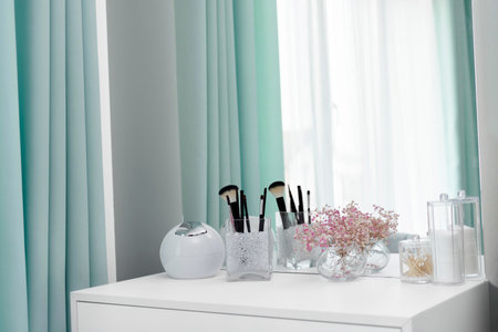 Makeup brushes are in a standing vase on a dressing table. The design of the dressing table is in an elegant modern bedroom. Makeup corner in the bedroom. Interior Minimalist Design.の写真素材