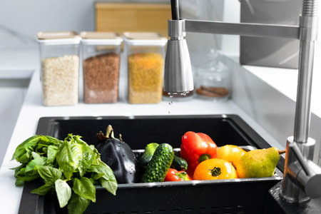 Fresh vegetables and fruits are washed in a special tray for vegetables. Drops of water are poured...