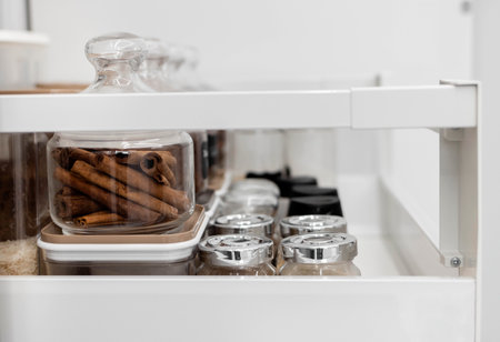 Close-up of jars of spices standing in a kitchen drawer. Storing spices in the kitchen. Home routine. Horizontal photo.の写真素材