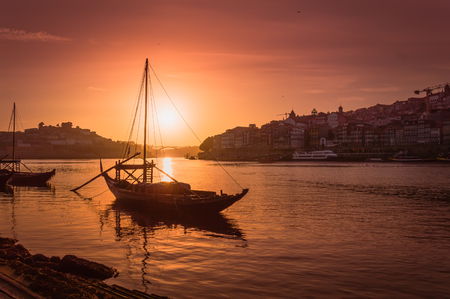 Porto at sunset: view over Duoro river with rabelo boat, Arrabida bridge and setting sun, Portugalの写真素材