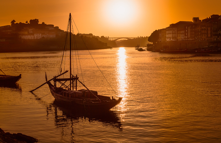 Porto at sunset: view over Duoro river with rabelo boat, Arrabida bridge and setting sun, Portugalの写真素材