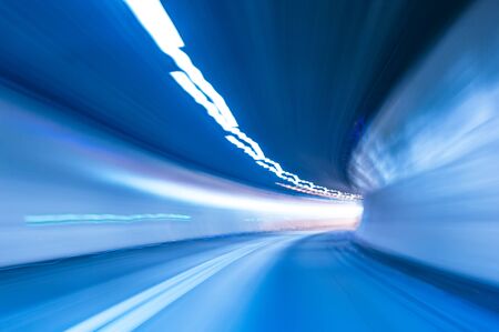 Speed motion in tunnel with curve. Abstract background in blue with motion blur and lights. Concept of speed and movementの写真素材