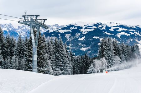 Mountains ski resort Zell am See Kaprun, Austria. Beautiful white winter landscape with snow, cable car over fir tree forest and snow cannon in snow-covered mountains on Schmittenhohe in Austrian Alpsの写真素材