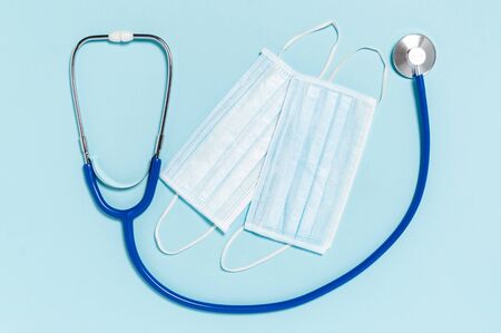 Coronavirus protection. Stethoscope and medical surgical masks on blue background. Infectious respiratory disease. Hygiene measures to prevent spread of Covid-19 pandemicの写真素材