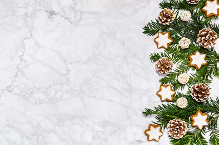 Plastic free winter flat lay with organic decoration: conifer tree branches, pine cones, cinnamon star cookies on marble background. Greeting card, copy space. Merry Christmas, Happy New Year holidayの写真素材