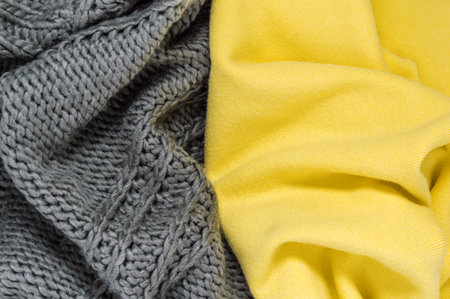 Knitted sweater or scarf as wool texture in trendy colors of year 2021 illuminating yellow and ultimate gray. Vivid textile background with fashionable winter clothes or accessories and copy spaceの写真素材
