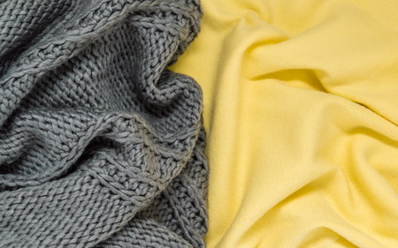 Knitted sweater or scarf as wool texture in trendy colors of year 2021 illuminating yellow and ultimate gray. Vivid textile background with fashionable winter clothes or accessoriesの写真素材