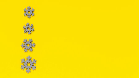 Grey wooden snowflakes on yellow background. Minimal winter backdrop in trendy colors of year 2021 illuminating yellow and ultimate gray. Copy space for textの写真素材
