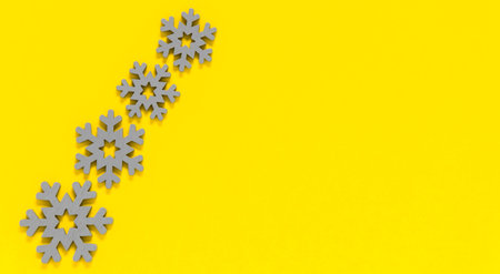 Grey wooden snowflakes on yellow background. Minimal winter backdrop in trendy colors of year 2021 illuminating yellow and ultimate gray. Copy space for textの写真素材