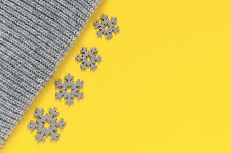 Grey knitted wool texture of sweater, scarf or knit cap and snowflakes in trendy colors of year 2021 illuminating yellow and ultimate gray. Fashionable warm autumn and winter clothes and accessoriesの写真素材