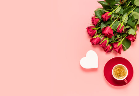 Red roses bouquet, white heart and cup of coffee on pink background. Birthday, mothers, women's or Valentines day celebration. Love and dating concept. Flat lay with copy space for textの写真素材