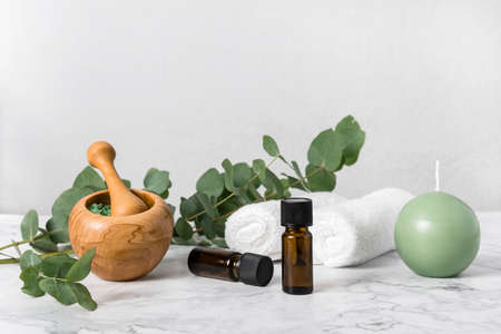 Natural aromatherapy with eucalyptus essential oil bottles and aromatic bath salts, candle and towels on marble. Zero waste spa, wellness and skin care products. Relaxation with eucalyptus extractの写真素材