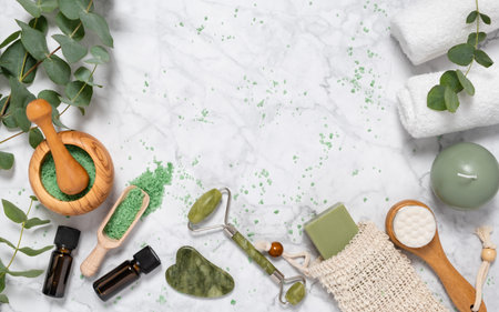 Natural skin care and aromatherapy with eucalyptus essential oil bottle, bath salt, beauty jade roller, gua sha on marble background. Spa, wellness, massage, relaxation concept. Top view, copy spaceの写真素材