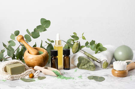 Natural skin care and aromatherapy with eucalyptus essential oil bottles, bath salt, beauty jade roller, gua sha on marble background. Spa, wellness, massage and relaxation conceptの写真素材