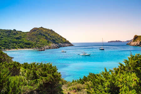 Boats in bay near Porto Timoni beach on Corfu island in Greece. Beautiful view of greek coast with green mountains, clear sea water and Pirate bay. Famous destination for summer vacationの写真素材