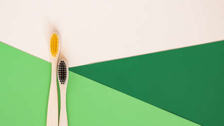 Eco-friendly bamboo toothbrush on geometrical beige and green background. Two natural wooden toothbrushes as plastic free dental care product. Zero waste, sustainable lifestyle. Flat lay, top viewの写真素材