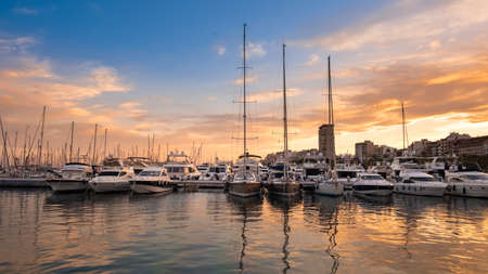 Alicante port with yachts and sailboats at sunset, Spain. Beautiful view of harbor in a touristic town in Costa Blanca region on Mediterranean sea coastの写真素材