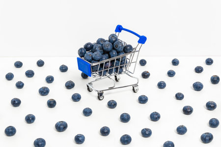 Blueberries in shopping cart and scattered berries isolated on white background. Shopping for...