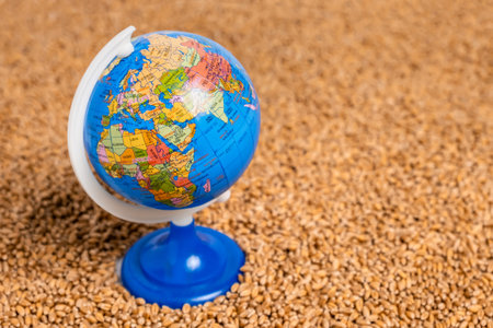 World globe on wheat grain pile as background. Concept of food shortage, grain supply crisis and...