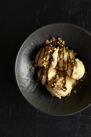 ice cream in a black bowl with nuts