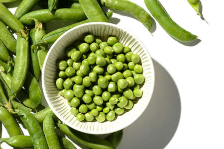 green peas and pods on a white backgroundの写真素材