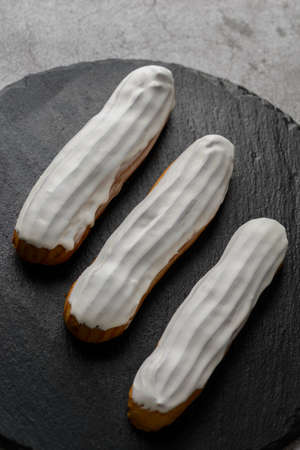 eclairs and tubes cakes on a black board. high quality photoの写真素材