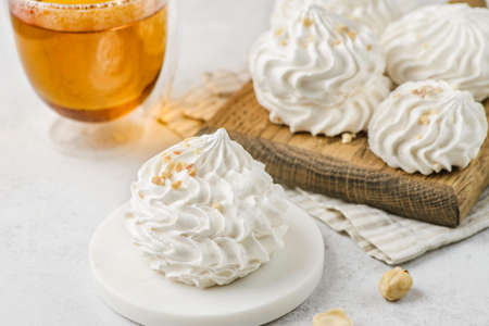 meringue on a wood on white background and glass of tea. meringue is a dessert made of whipped proteins in sugar.の写真素材