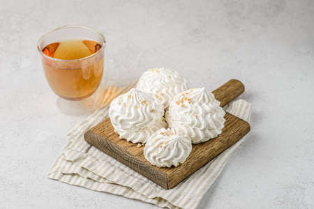 meringue on a wood on white background with tea. meringue is a dessert made of whipped egg whites with sugar. flat layの写真素材