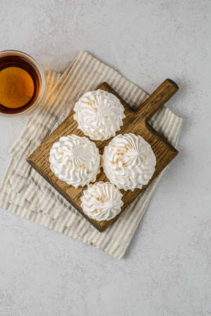 meringue on a wood on white background with tea. meringue is a dessert made of whipped egg whites with sugar. flat layの写真素材