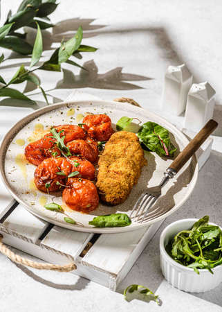 black tomato with oil and oragano on a plate. Decorated with arugula and greensの写真素材
