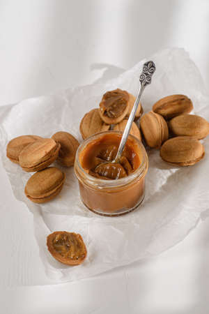 cookies nuts with boiled condensed milk. Cookies are in a white parchment, there is a jar of caramel next to itの写真素材