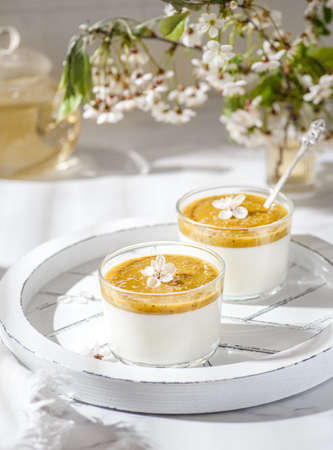 panna cotta with mango puree and chia seeds on a white tray on a bright sunny dayの写真素材