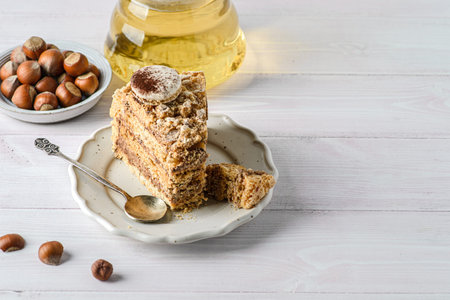 meringue cake with nut cream. Pieces of Esterhazy cake on a light background, next to tea and...