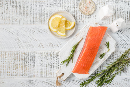 a piece of lightly salted salmon with lemon. Salmon is lying on the board, next to salt, chopped...