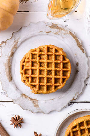 pumpkin waffles on a white wooden background. waffles made from pumpkin puree, eggs and flour, with the addition of cinnamon, clovesの写真素材