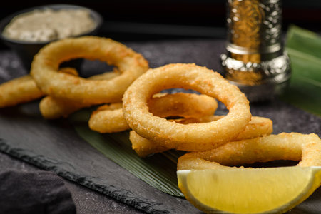 onion or calamari rings in breadcrumbs on a black board. high quality photoの写真素材