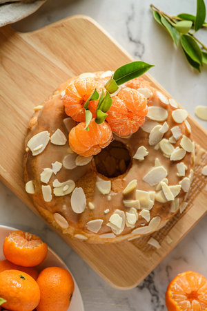 round gluten-free almond flour cake with tangerines on a white marble background, decorated with almond petalsの写真素材