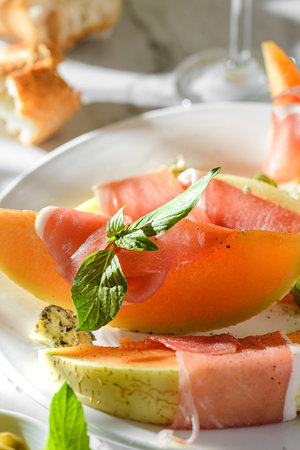 melon with parma and cheese on a marble backgroundphoto, white wine, baguette, olives, antipasti,の写真素材