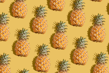 pineapple on a yellow background pattern, pineapple laid out on the backgroundの写真素材