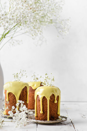 Easter cakes with yellow glaze on a table against a white wall with copyspace . high quality photo