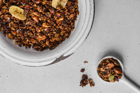 granola baked with nuts and honey with dried banana and milk on white table. Near cup of coffee, High quality photoの写真素材