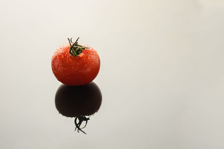 small tomato on the background with reflection with drops. high quality photoの写真素材