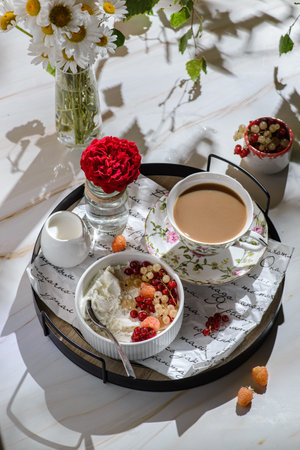 cottage cheese with berries and coffee for breakfast. decorated with currants and raspberries, next to a coffee mug and a creamerの写真素材