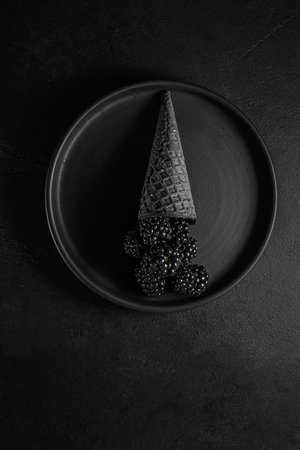 blackberries on a black background in an ice cream coneの写真素材