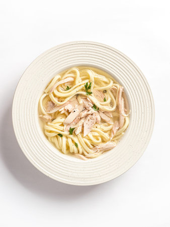 chicken noodle soup with herbs in a white bowl. High quality photo