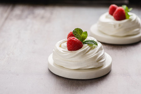 Pavlova meringue dessert with raspberries and cream. The dessert is made from egg whites and powdered sugar, as well as whipped cream and cottage cheese. Decorated raspberry and mintの写真素材