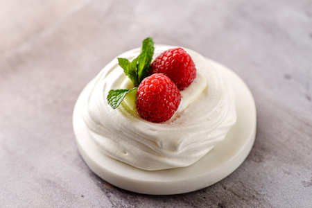 Pavlova meringue dessert with raspberries and cream. The dessert is made from egg whites and powdered sugar, as well as whipped cream and cottage cheese. Decorated raspberry and mintの写真素材