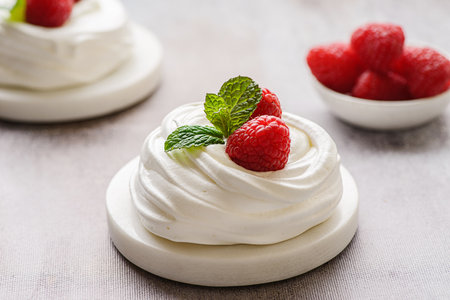 Pavlova meringue dessert with raspberries and cream. The dessert is made from egg whites and powdered sugar, as well as whipped cream. Decorated raspberry and mintの写真素材