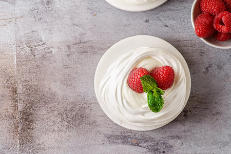 Pavlova meringue dessert with raspberries and cream. The dessert is made from egg whites and powdered sugar, as well as whipped cream and cottage cheese. Decorated raspberry and mintの写真素材